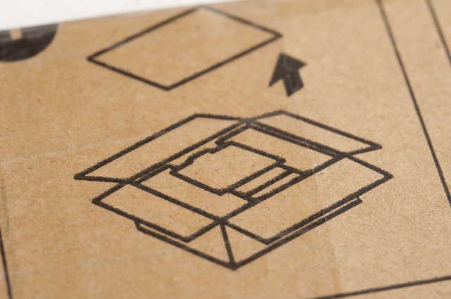 Operating instructions for packaging stamped on a brown cardboard box with a diagram showing how to open it