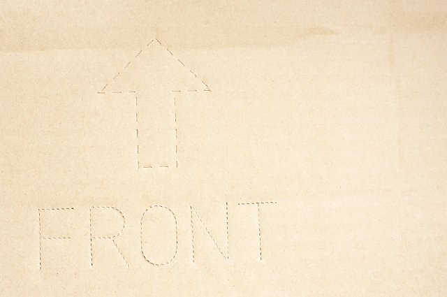 Close up background of cardboard box wall with perforated text describing front with upward arrow
