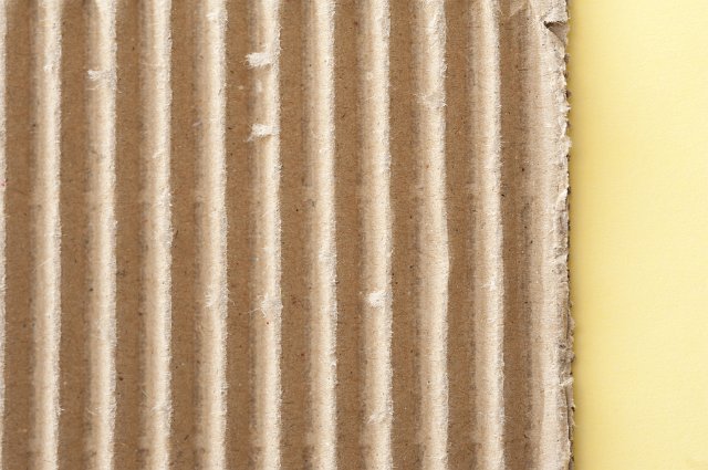 Corrugated brown cardboard background used for strengthening packaging materials in a close up view with yellow copy space to the right