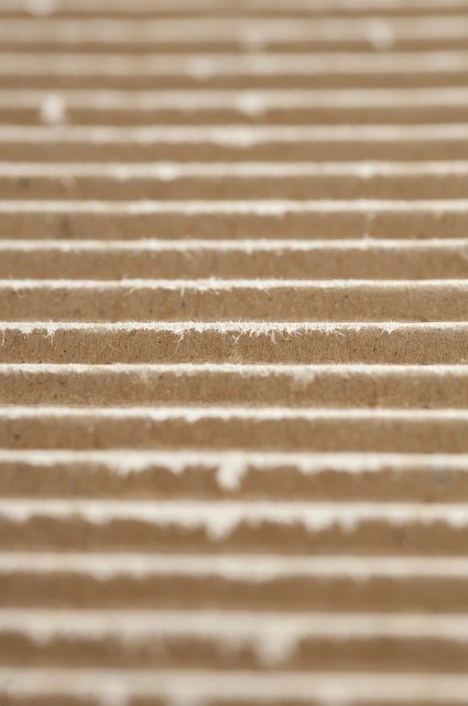 Background texture of brown corrugated cardboard viewed low angle with shallow dof accentuating the ridges