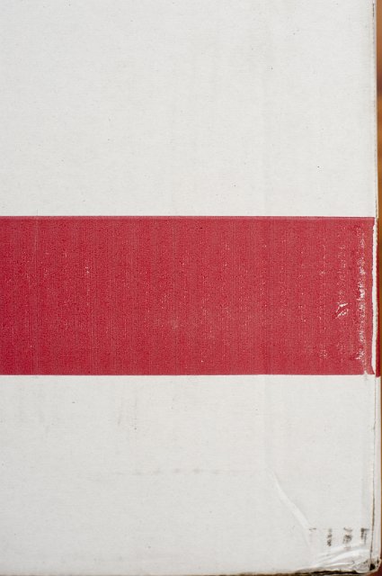 Packing carton background texture with a close up view of a white cardboard box with a broad red band running across it