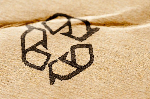 Recycle symbol on a cardboard background texture on commercial packaging with copy space alongside
