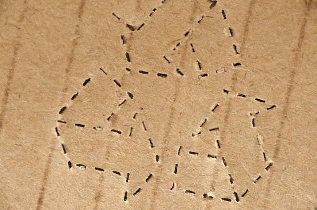 Perforated recycle icon stamped on brown cardboard packaging in a close up view