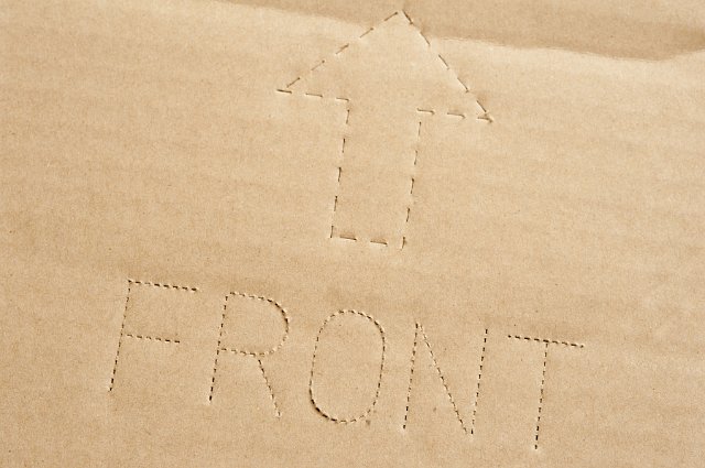 Extreme Close Up of Corrugated Cardboard Box with Arrow Pointing to Front of Package, Direction on How to Pack and Store - Close Up Shipping Concept Background