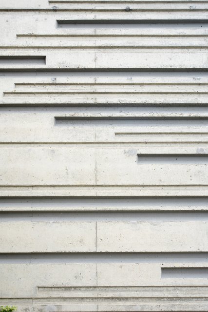 A close up of a white, textured, moulded concrete wall.