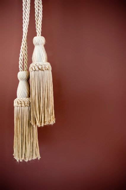 ornate gld coloured curtain tassels on a brown background
