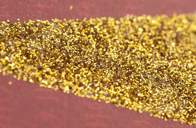 Abstract Close Up of Golden Glitter Spilled on Pink Surface, Gold Metallic Glitter in Triangular Shape Ideal for Backgrounds