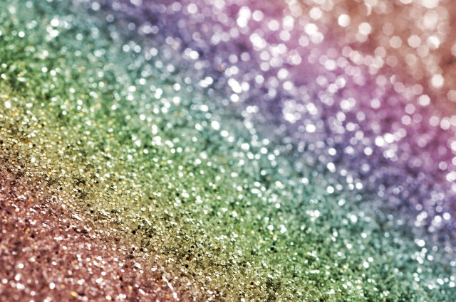 Rainbow colored glitter background in the colors of the spectrum arranged in a diagonal line for holiday or festive themed concepts