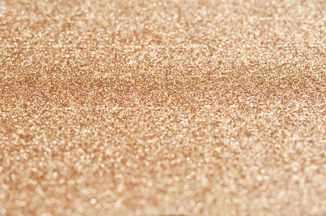Abstract Background of Sparkling Gold Glitter Spread Across Full Frame in Selective Diffuse Focus with Copy Space