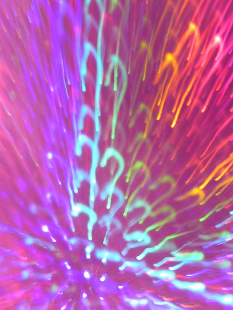 brightly colours motion blurred light trails that look like a matrix of coloured question marks