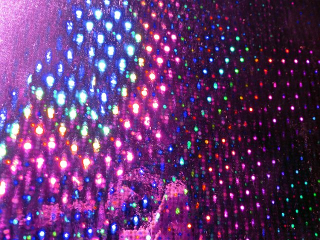 iridescent colorful background of light dots refecting on a holographic surface