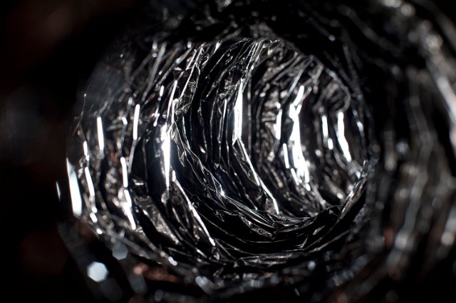 a view down a metal foil duct with light at the end