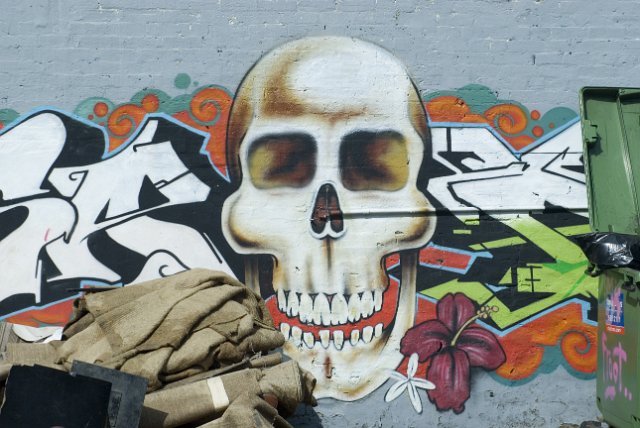 a wall covered in graffiti with a skull motif