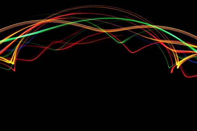 a colorful arch of light trails on a black background with plenty of copyspace below