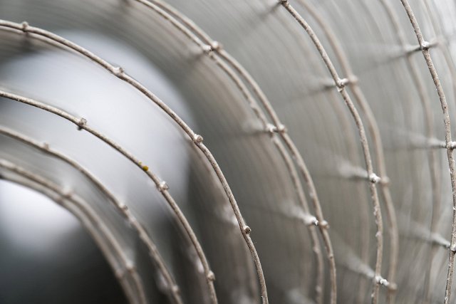 Abstract concentric circular pattern formed by a roll of fencing wire mesh viewed end onto the coils with shallow dof