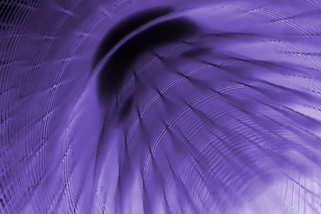 Purple metal grid abstract background in a full frame view looking down a coiled roll of wire with soft focus effect
