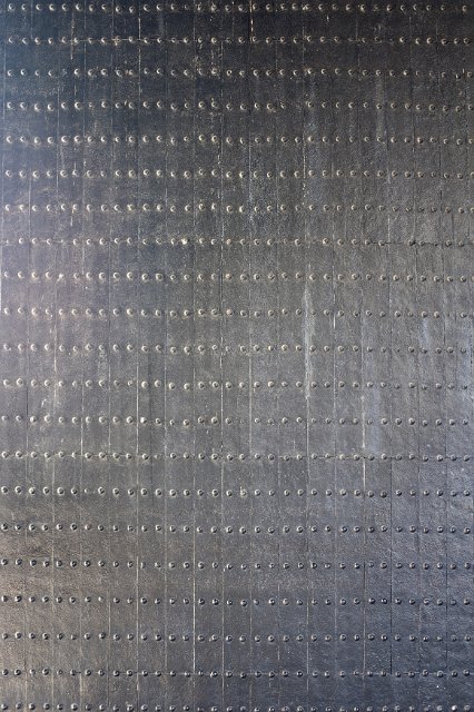 An isolated shot of a plated steel door and rows of rivets.