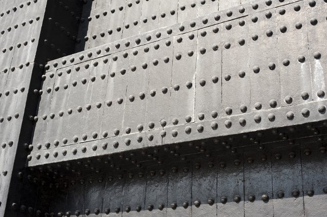 A close up of a large structural metal girder and multiple rivets.