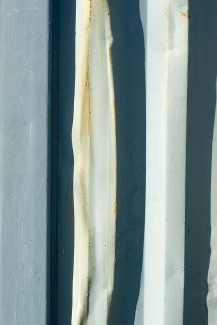 A close up of a blue and white, rusty, aged corrugated iron sheet.