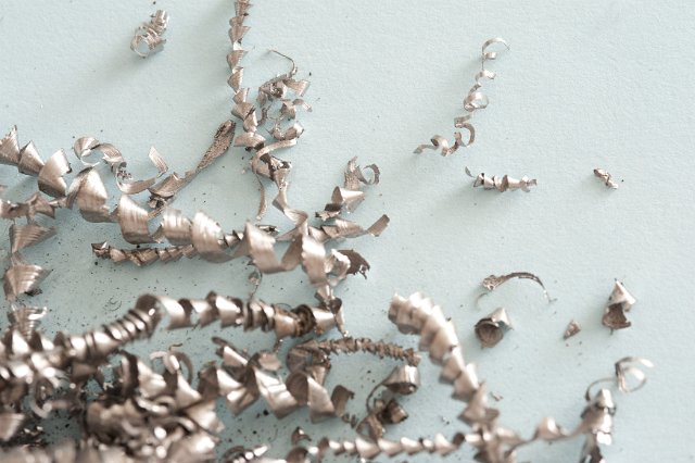 Scattered steel shavings, chips, filings or swarf produced as a waste product during industrial machining on a white background