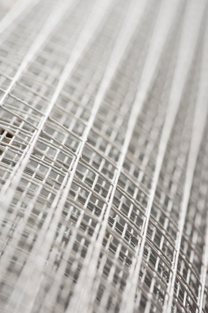 Close up of coiled roll of square grid fencing wire with a shallow depth of field.