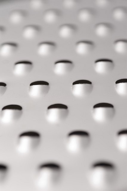 Background texture of a steel grater with selective focus to the centre in a full frame view