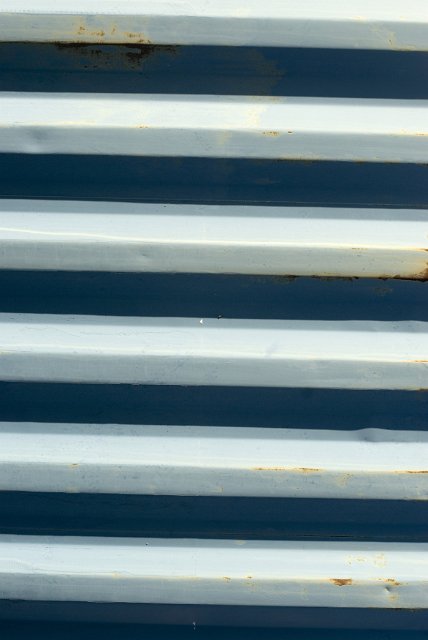 A close up of an aged blue and white corrugated iron roofing sheet.