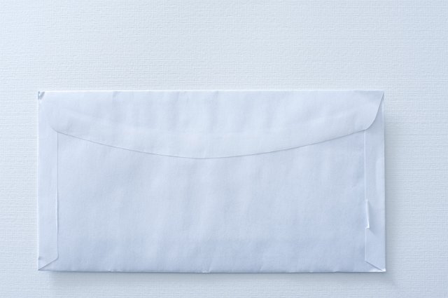 a white envelope with distressed corners on a textured paper backdrop
