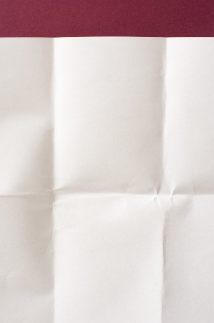 a sheet of creased blank paper with a red background border at the top