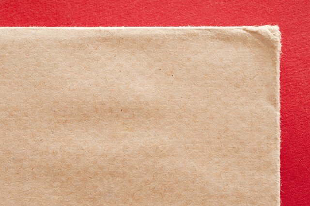 a brown envelope corner pictured on a red background
