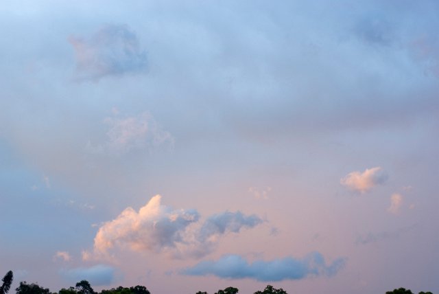a cloudy sky illuminated with pink light and contrasting grey blue tones