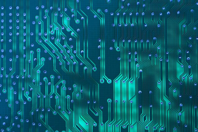 Background pattern of blue electronic circuit tracks on a motherboard in a closeup full frame view