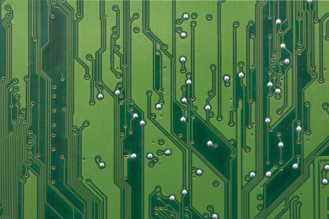 A close up detailed shot of a green circuit board and wiring.