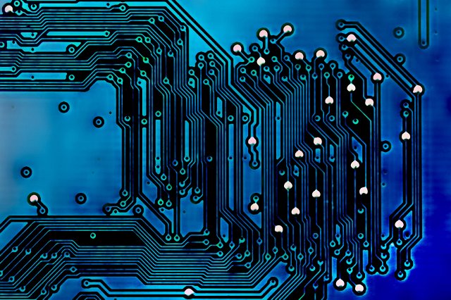 Colorful blue electronics circuit board backdrop with parallel tracks and components in a close up full frame view