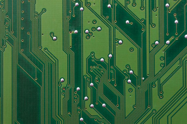 Green electronic circuit board pattern with track connections. Close-up full frame background concept