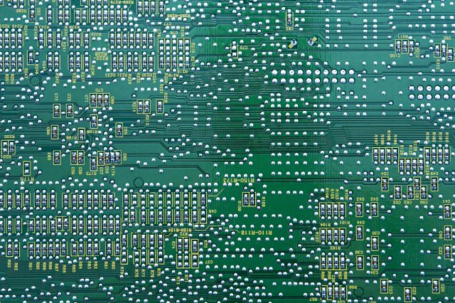 A detailed, close up shot of the underside of a green circuit board.