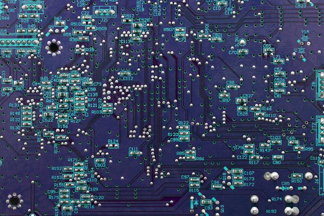 Printed purple electronic circuit background with resistors, transistors, capacitors, inductors and diodes in close up detail