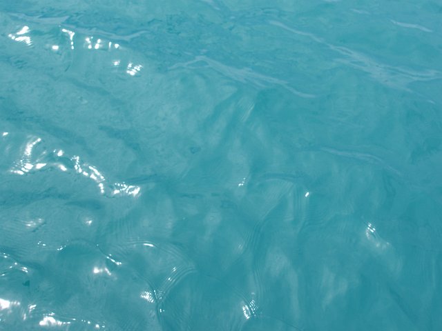 the texture of aqua-marine blue water surface with light reflecting of small waves