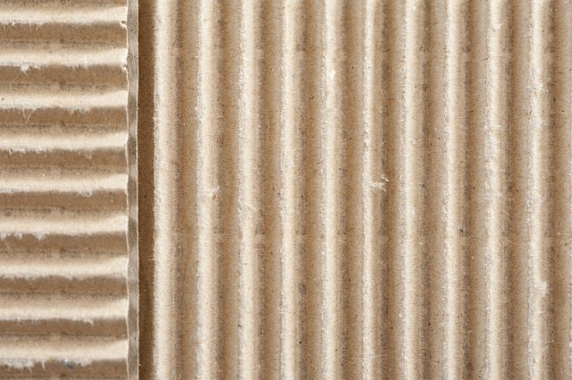 Two corrugated surfaces of brown paper packaging material set at right angles to each other in an overhead full frame background texture view