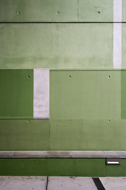 Modern green concrete wall with shaded panels in different hues in an architectural background
