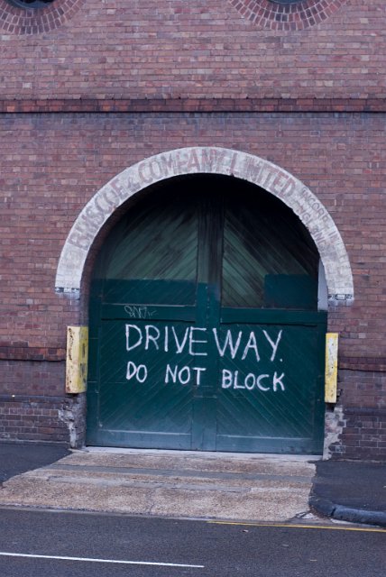an old brick warehouse facade, doors painted with driveway do not block