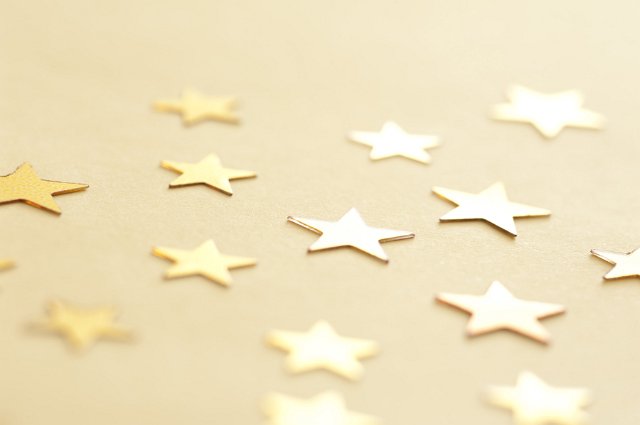Close Up of Gold Stars Scattered on Neutral Yellow Background, Abstract Success Concept Background