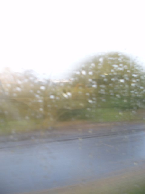 rain on a misted up window and a road outside