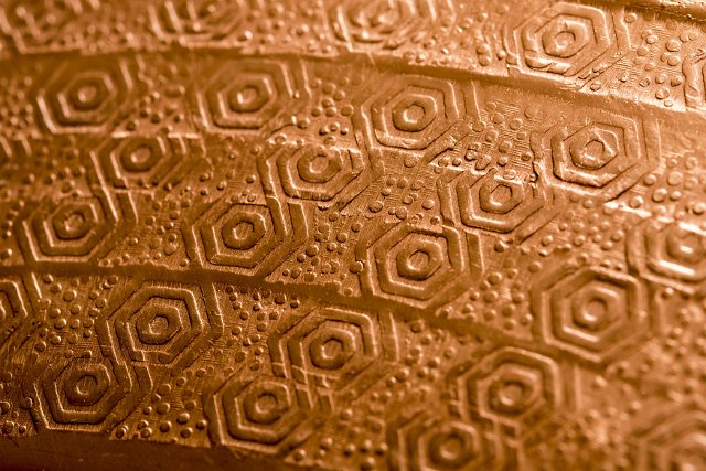 Decorative copper stamped or pressed with a repeat geometric pattern in a close up full frame view