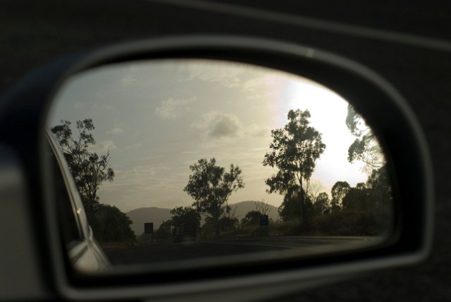 a car side mirror looking back in the evening sun
