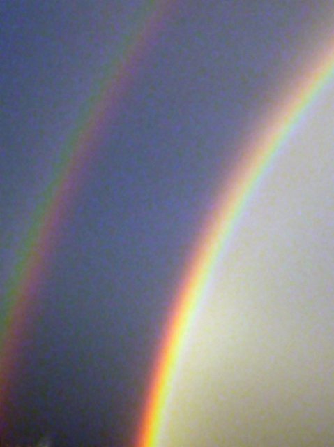 a black stormy sky with double rainbow arching across