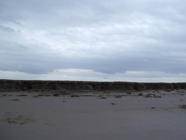 a bleak landscape of cloudy sky and eroded sand banks