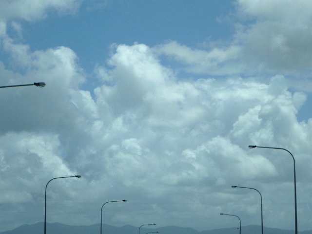 an avenue of street lights pictured against a clouded sky