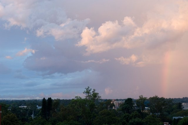 a stormy sky with a rainbow alongside pink and blue clouds