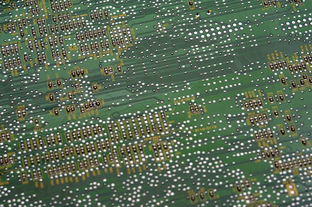 Electronic circuit components soldered on green circuit board, viewed in close-up full frame background concept